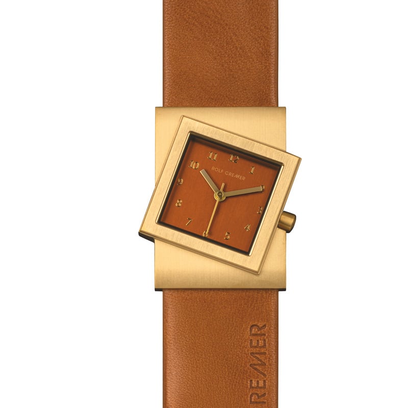 Orologio Rolf Cremer con cassa quadrata dorata e quadrante arancione, cinturino in pelle marrone.