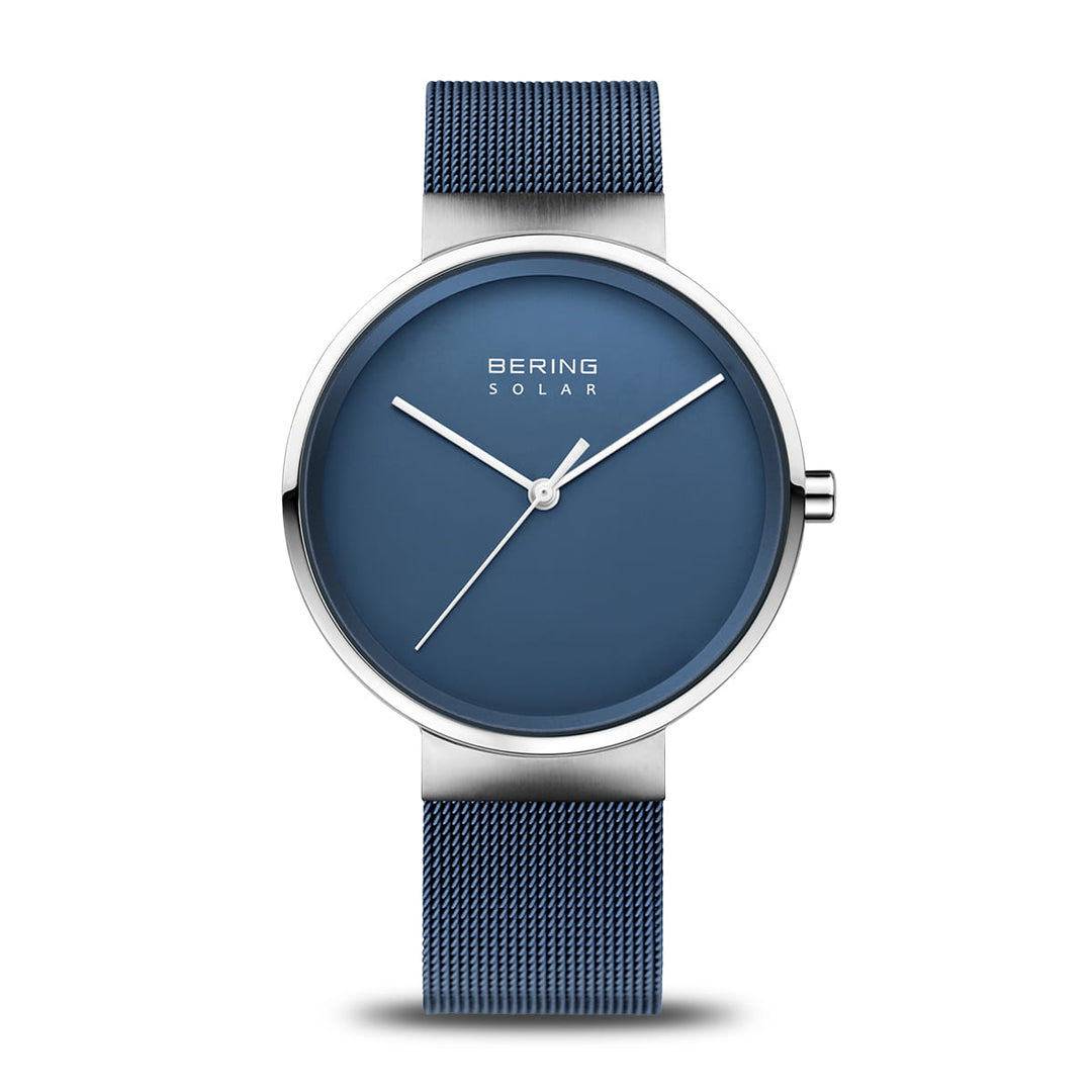 Dit elegante Bering polshorloge, model 14339-307, heeft een blauwe wijzerplaat met minimalistische zilveren uur- en minutenwijzers, geen cijfers, de tekst Bering Solar Horloge, een bijpassende blauwe mesh-band en een zilveren lunette voor een moderne stijl.