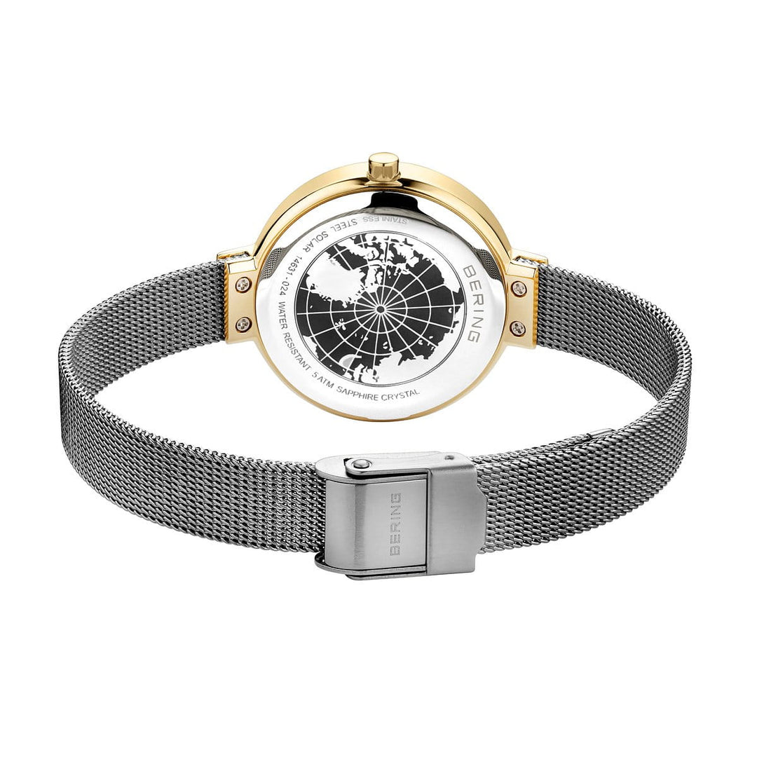 De achterkant van het Bering dameshorloge 14631-024 toont een gouden lunette en zilveren mesh band. Dit quartz-aangedreven horloge heeft een gegraveerd kaartontwerp, met BERING en SAFFIERGLAS, terwijl de sluiting is gemarkeerd met het Bering-logo.