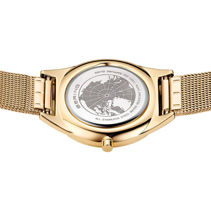 De afbeelding toont de achterkant van een Bering 17031-333 dameshorloge met een gouden meshband. De achterkant van de kast toont een kaartontwerp en inscripties zoals BERING en All Stainless Steel. Het horloge bevat een quartz uurwerk, ronde kast, zichtbare kroon en duurzaam saffierglas.