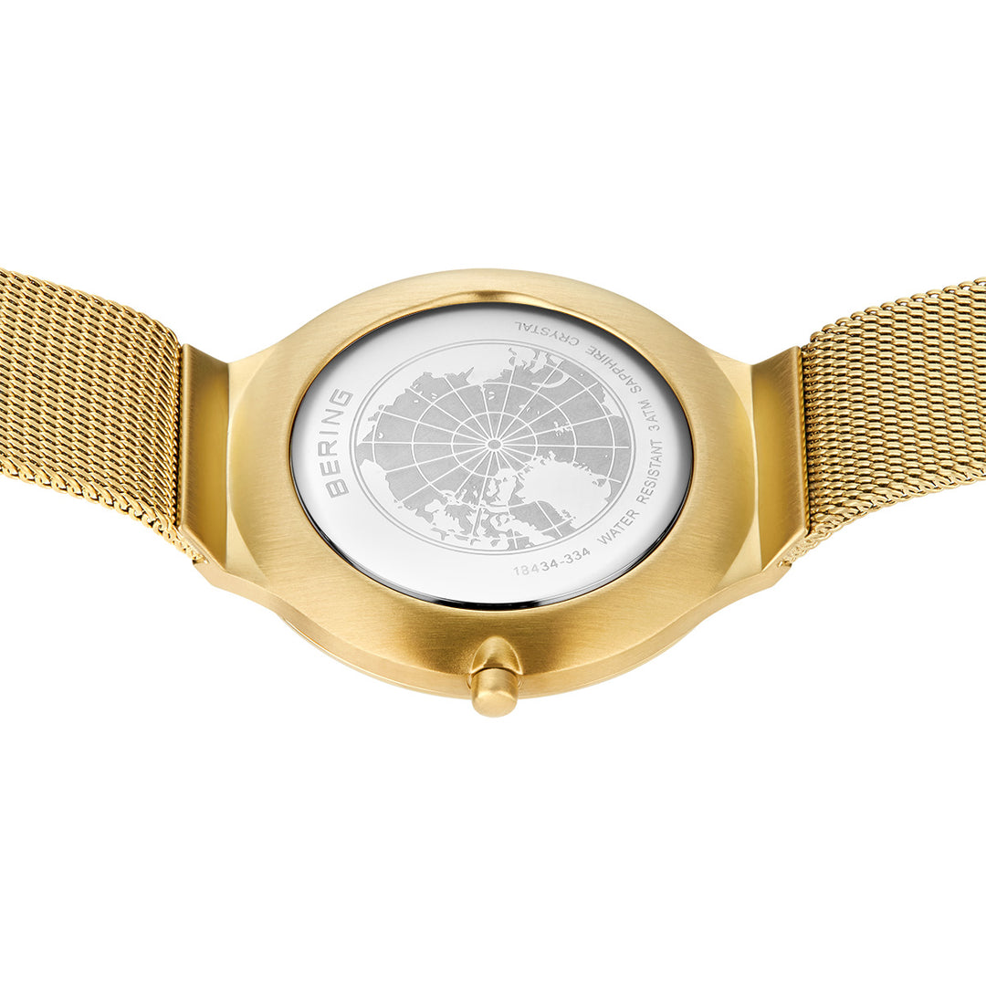 Op de achterkant van het Bering dameshorloge goud - 18434-334 is een wereldkaart gegraveerd op de gouden meshband van het horloge, met het label BERING en informatie over de waterbestendigheid en het modelnummer.