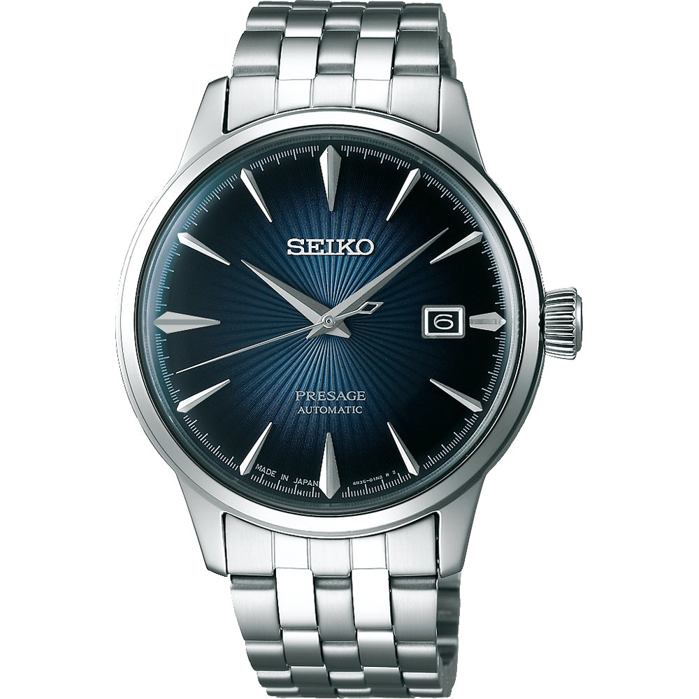 Het Seiko Presage Heren Horloge SRPB41J1 heeft een roestvrijstalen band, een waterdichte constructie, een diepblauwe sunburst wijzerplaat met zilveren uurmarkeringen en wijzers, een datumvenster op 3 uur en een strakke zilveren lunette.
