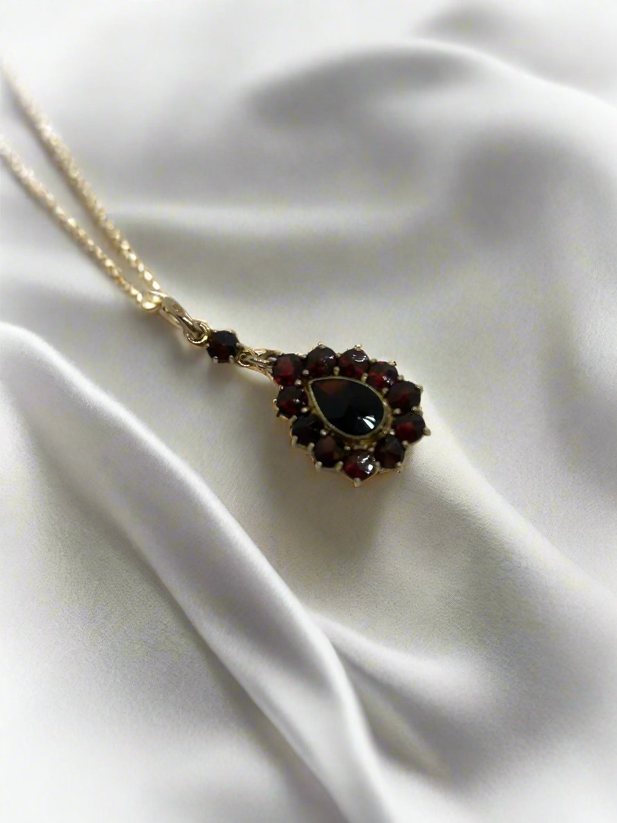 Ciondolo vintage in oro 14k con granato, forma a goccia circondata da pietre granate.