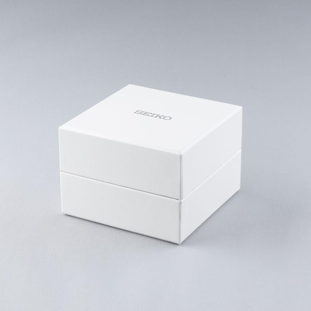 Op een lichtgrijs oppervlak staat een witte vierkante Seiko-doos, minimalistisch met het Seiko-logo erop. Het belooft de elegantie van een verfijnde schat: het Seiko heren horloge SSB425P1, gehuisvest in een strakke roestvrijstalen kast.