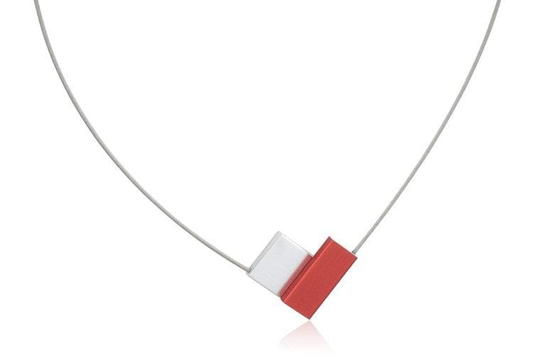 Collana a V con elementi rossi e bianchi su corda metallica.