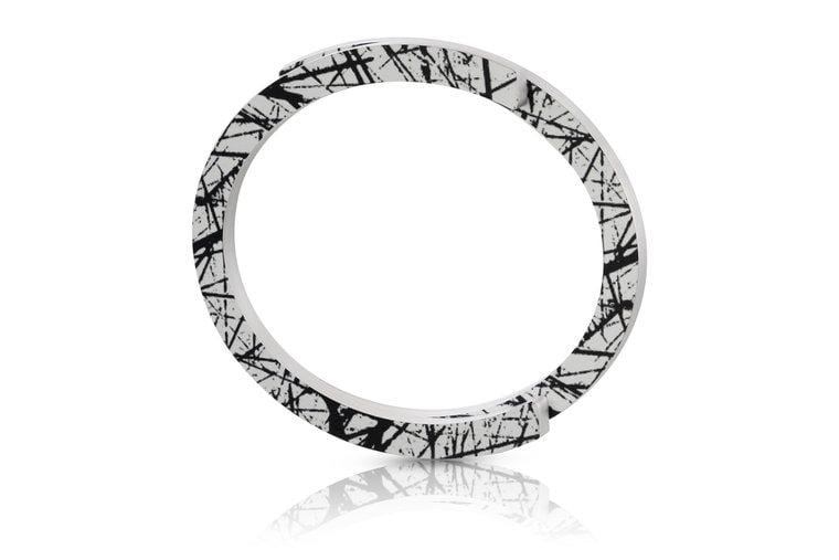 Bracciale bianco con motivo astratto nero, forma circolare e finitura lucida.