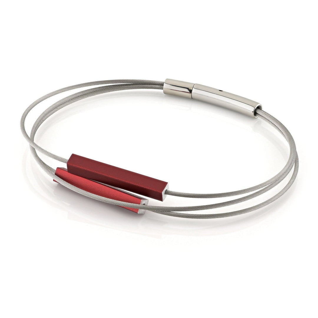 De Armband staafjes Rood A243R van CLIC Creations is een strakke, minimalistische armband met in elkaar verweven dunne zilveren banden en rode accenten, handgemaakt in Nederland. Het heeft een gemakkelijke bajonetsluiting voor veiligheid en straalt moeiteloze elegantie uit tegen een witte achtergrond.