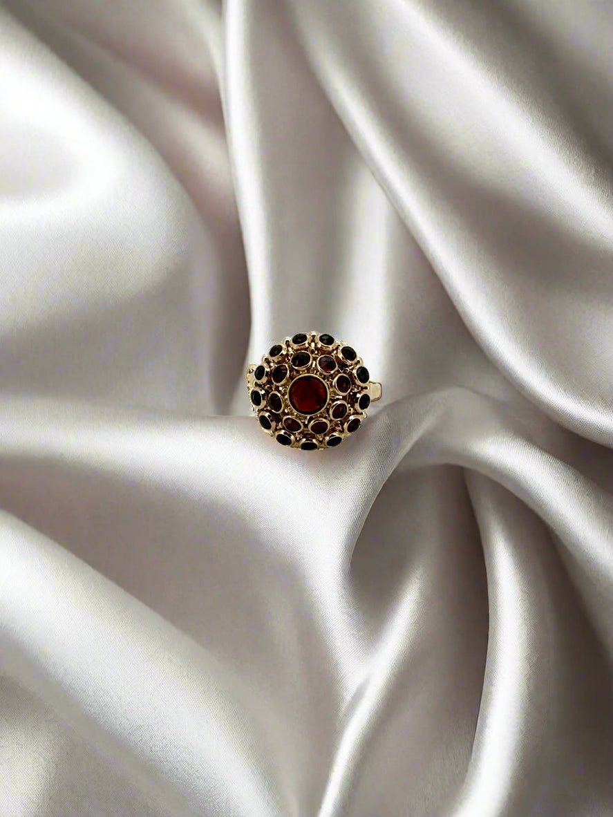 Anello vintage in oro 14k con granato centrale e pietre nere.