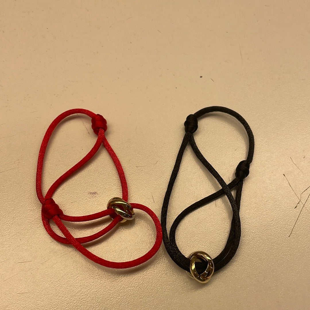 Bracciali in corda rossa e nera con dettagli in metallo dorato.