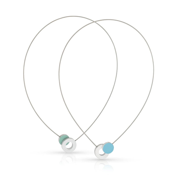 De Collier Gekleurd rondje en een ring C265B van CLIC Creations heeft een minimalistisch ontwerp met dunne zilveren draden die twee lussen vormen, een ronde zilveren hanger met een turquoise kraal en een magnetische sluiting. Het is strak, eigentijds en handgemaakt in Nederland.
