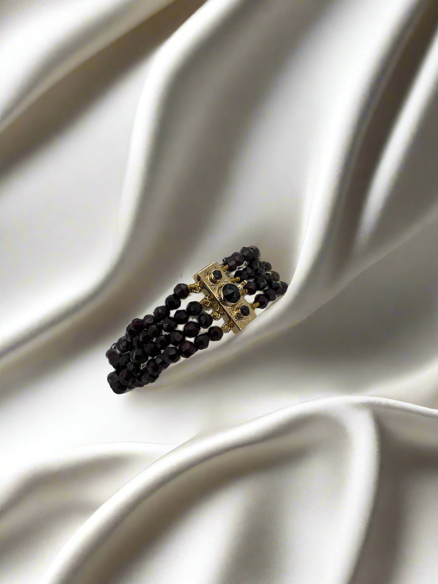 Bracciale vintage in oro 14k con granati, dal design intrecciato e pesantezza di 25,5 gr.