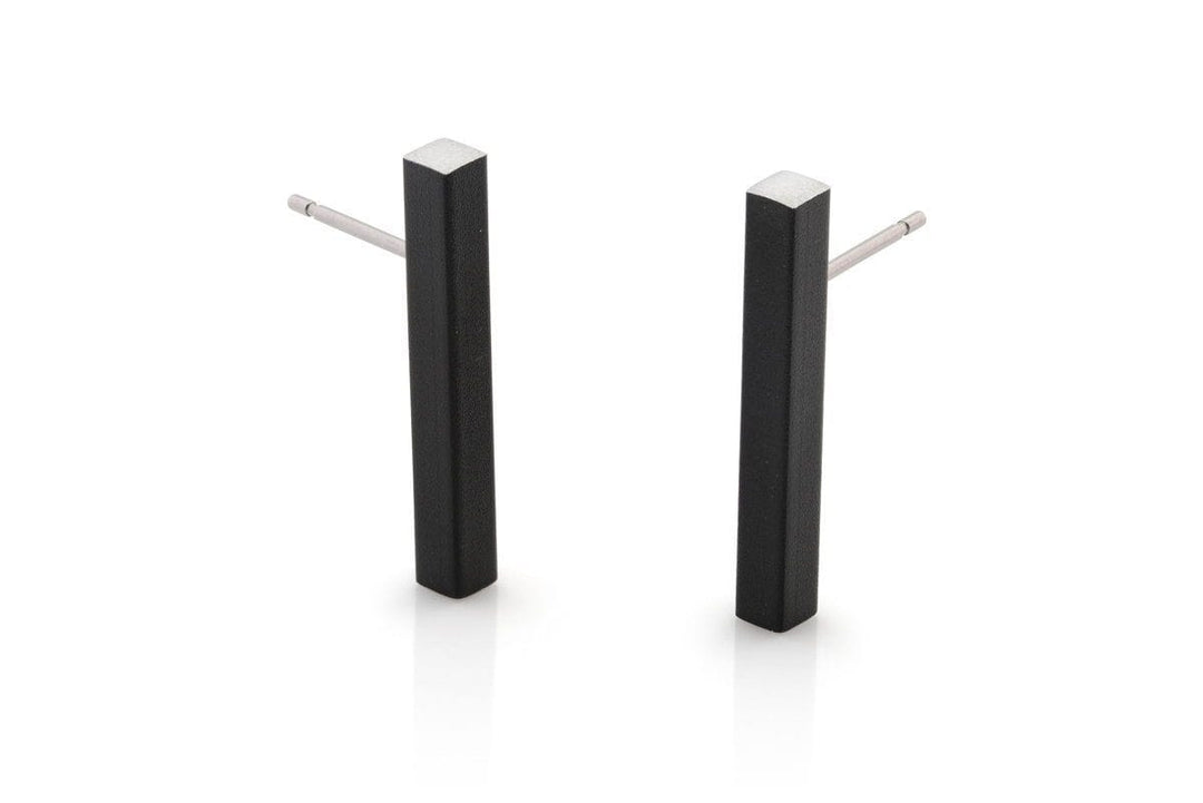 De Oorsteker Staafje Zwart O26Z van CLIC Creations is een paar minimalistische zwarte rechthoekige oorbellen met zilveren stekers, handgemaakt in Nederland. Ze hebben een strak design en matte afwerking, afgebeeld tegen een witte achtergrond voor een elegante touch.