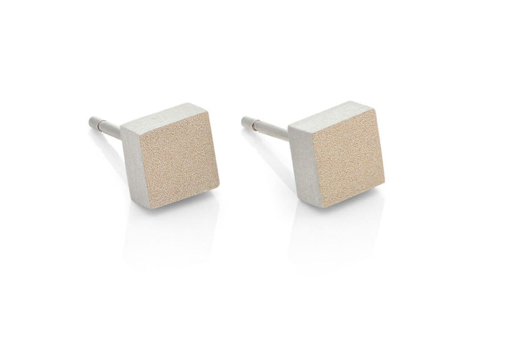 De Oorsteker Klein vierkant Goud O37G van CLIC Creations bestaat uit twee vierkante oorstekers met een geborstelde metalen afwerking op een witte achtergrond. Deze oorbellen tonen hypoallergene eigenschappen, een minimalistisch ontwerp met gladde randen en reflecterende oppervlakken die in elk handgemaakt detail een uniek design belichamen.