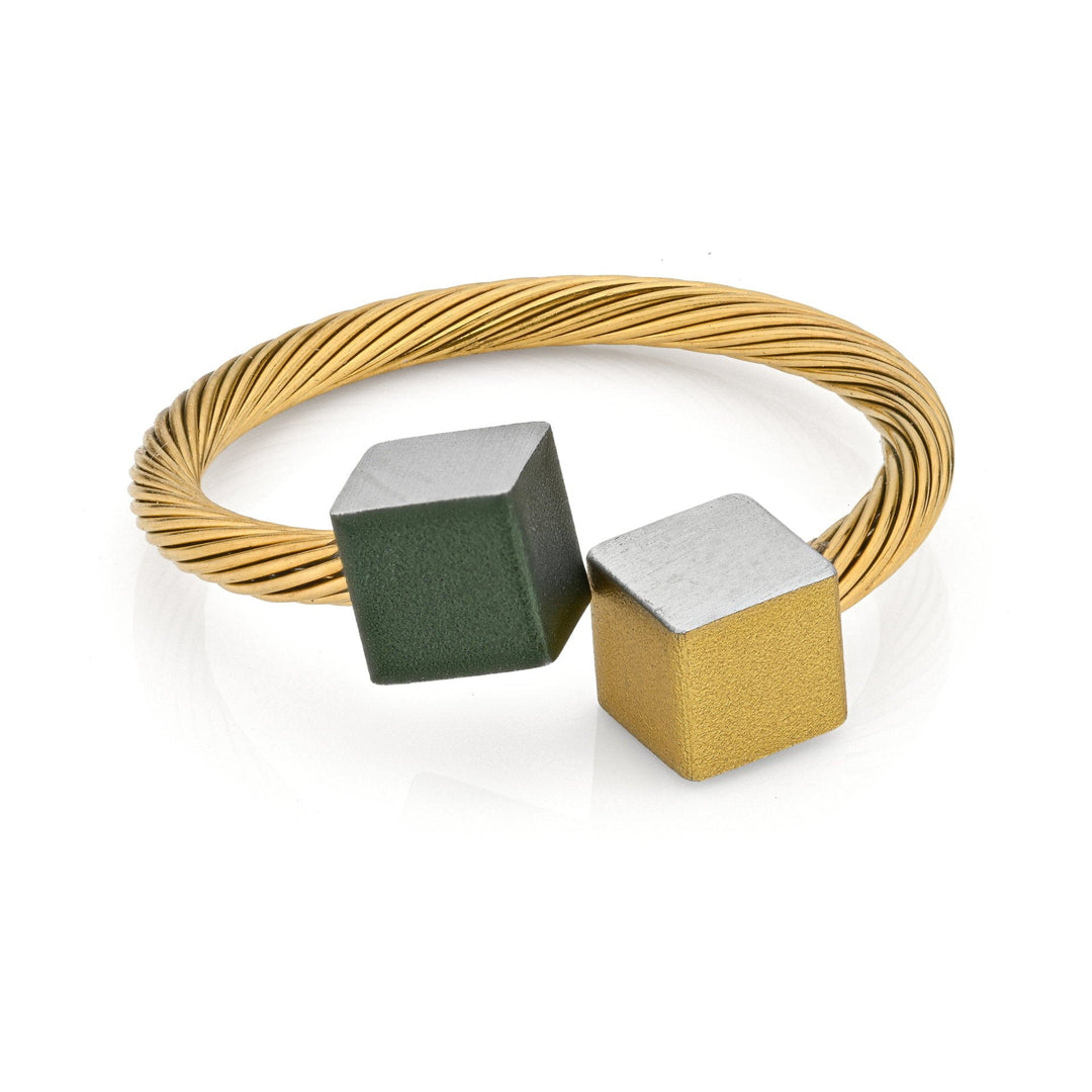 De CLIC Creations Goudkleurige Ring Kubusjes Groen Goudkleurig RG4GRG heeft een gedraaide goudkleurige band met open uiteinden, elk versierd met een groen en zilveren kubus of een goud en zilveren kubus, vervaardigd uit chirurgisch edelstaal voor een minimalistische stijl.