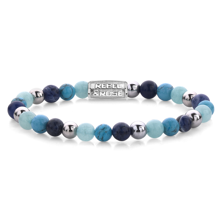 De Blue Summer Vibes - 6mm Kralen Armband Dames van Rebel & Rose heeft afwisselend blauwe, turquoise en zilveren kralen met een rechthoekige zilveren bedel waarin de merknaam is gegraveerd.