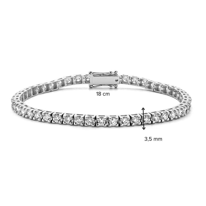 De Excellent Jewelry Witgouden Tennisarmband met 63 briljanten (3.01 crt, 14 karaat) heeft een veilige sluiting, is 18 cm lang en 3,5 mm breed; afmetingen zijn met zwarte pijlen aangegeven.
