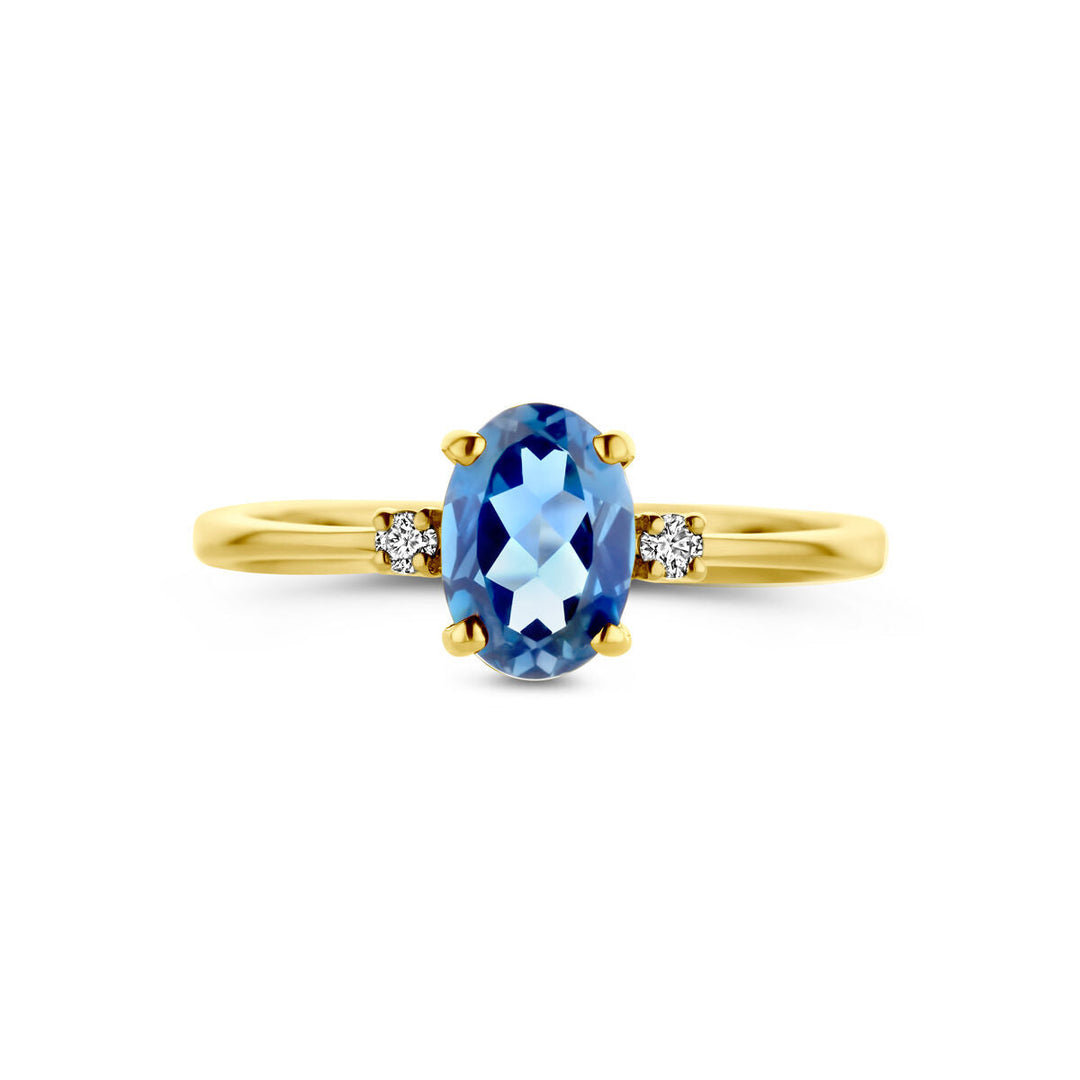 De ringtrilogie van de Van der Kooij Collectie heeft een 14K geelgouden band met een ovale London Blue topaas en twee kleine ronde diamanten (0,04 ct H SI) aan elke kant, tentoongesteld tegen een witte achtergrond.