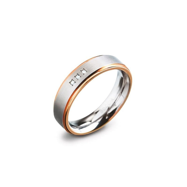 De Boccia Titanium Ring Bicolor rgp dia 3/0.015 - 0134-02 van Boccia heeft roségouden randen en drie kleine diamanten op een rij op het matte zilveren oppervlak, afgebeeld op een witte achtergrond.
