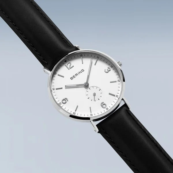 De Bering 14040-404 is een minimalistisch herenhorloge met een witte wijzerplaat, zilverkleurige kast, zwarte leren band, eenvoudige markeringen, quartz uurwerk en zilverkleurige 12, 3, 6, 9 cijfers plus een kleine subdial boven de 6.