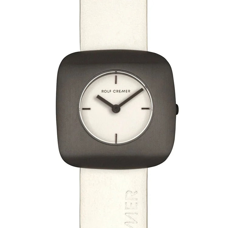 Orologio quadrato Rolf Cremer con cassa nera e quadrante bianco, cinturino in pelle chiara.