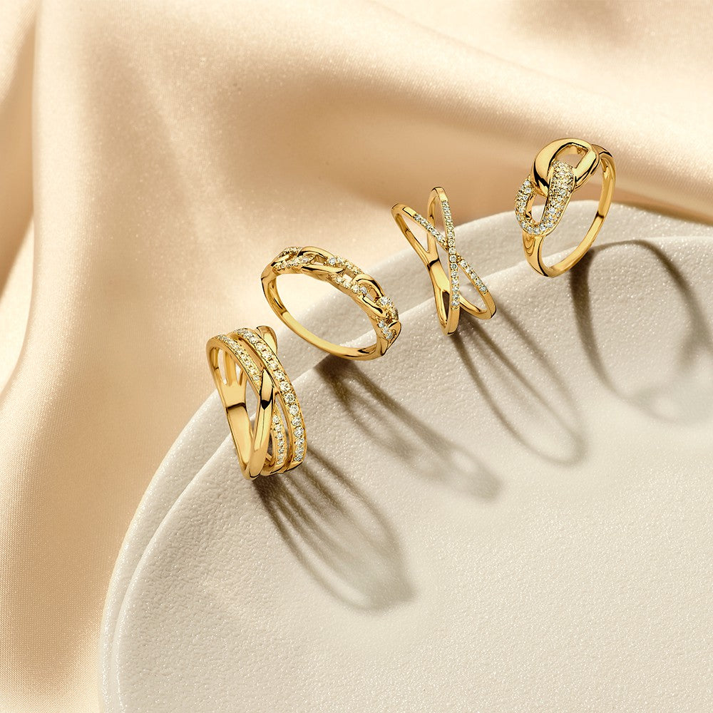 De Geelgouden Ring met Verbonden Schakels en Diamant van Excellent Jewelry schittert elegant op een lichtbeige ondergrond met satijnen stof - een 14 karaat luxe damesjuweel perfect gepresenteerd.