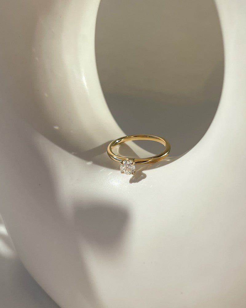 De Elegante Gouden Solitair Ring met 0,40 crt Briljant van Excellent Jewelry straalt subtiele luxe uit op een gladde witte keramische ondergrond in zacht natuurlijk licht met delicate schaduwen.