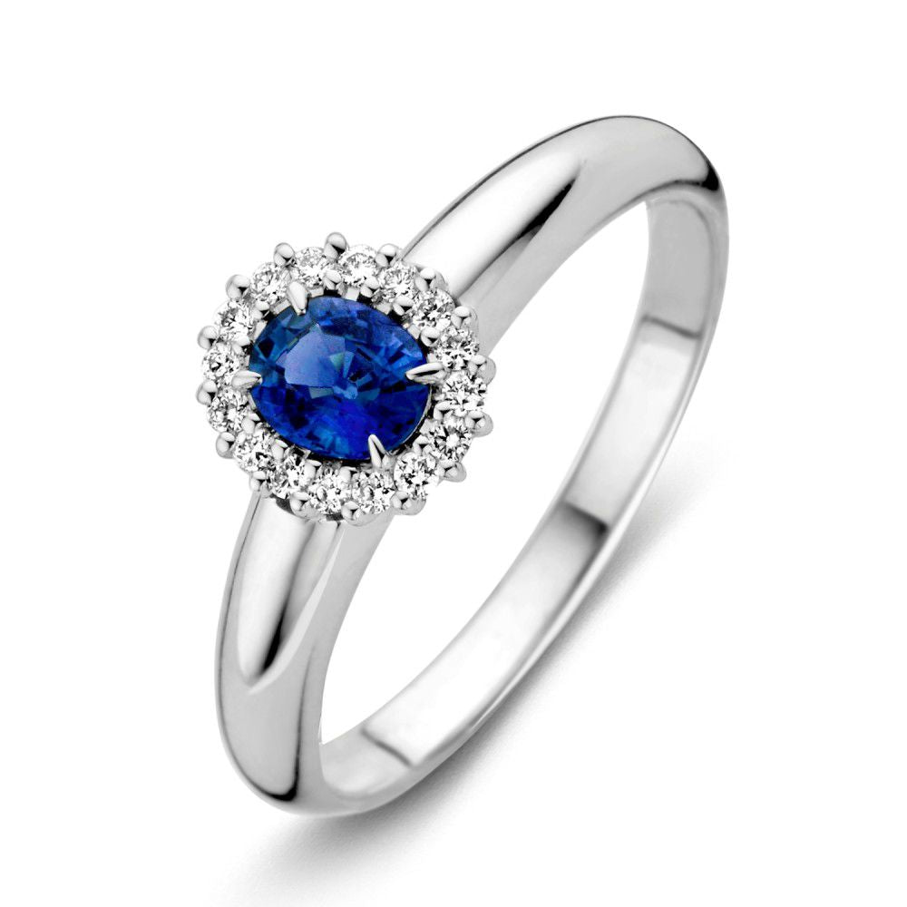 Anello in oro bianco con zaffiro blu ovale e diamanti, design elegante e raffinato.