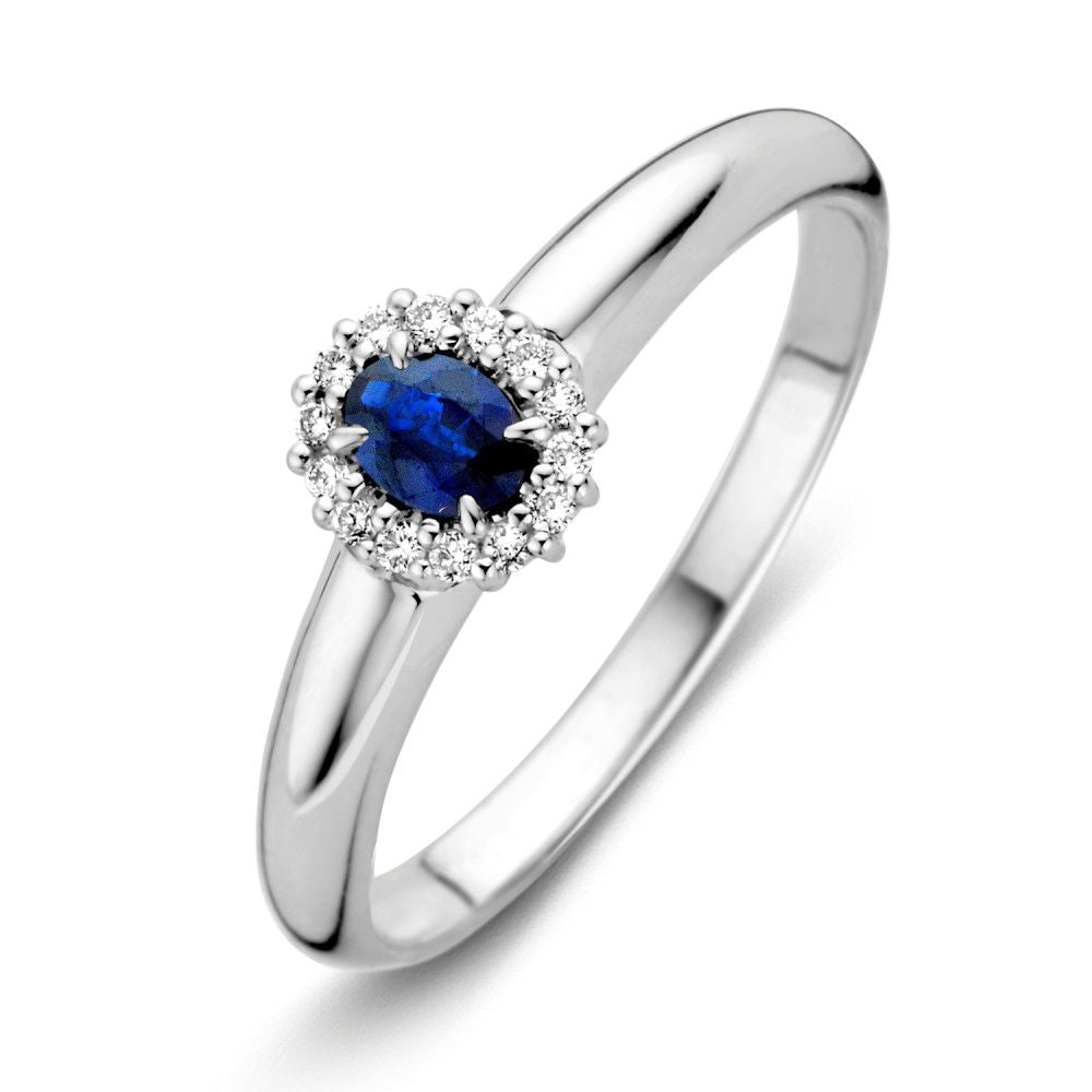 Anello in oro bianco con zaffiro blu ovale e diamanti circondanti.