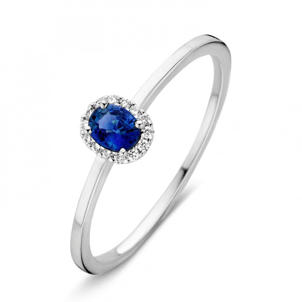 Anello in oro bianco con zaffiro blu ovale e diamanti, design sottile e raffinato.