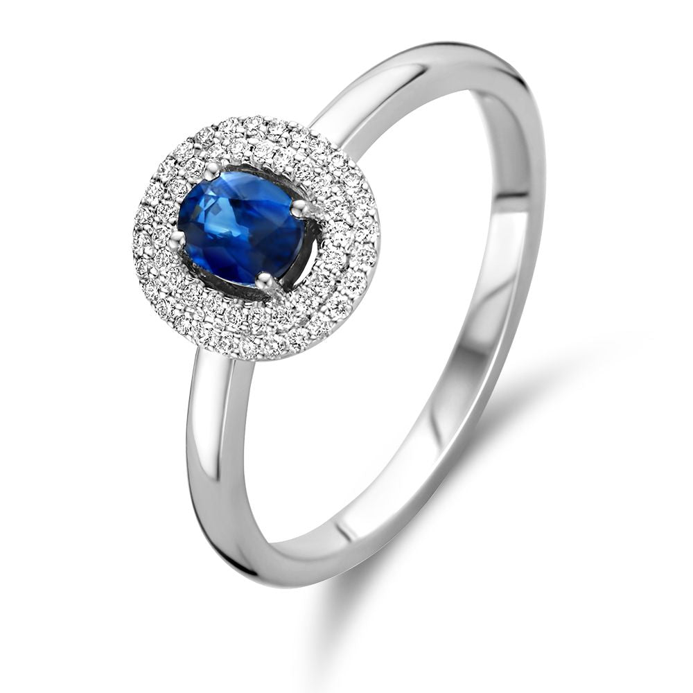 Anello in oro bianco con brillante e zaffiro centrale, circondato da piccoli diamanti.
