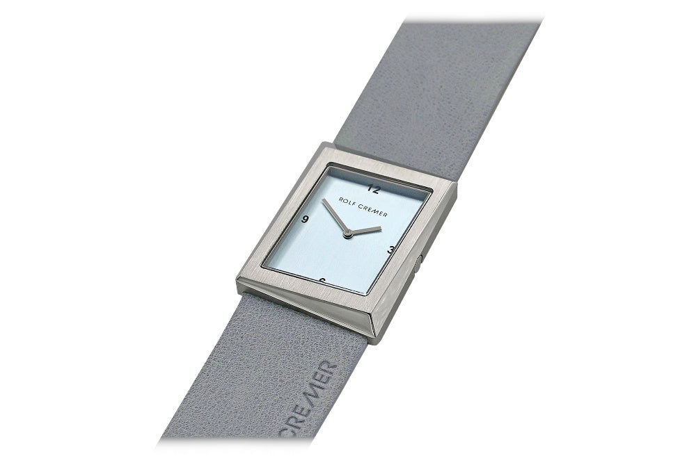 Orologio quadrato Rolf Cremer con cassa argentata e cinturino grigio in pelle.