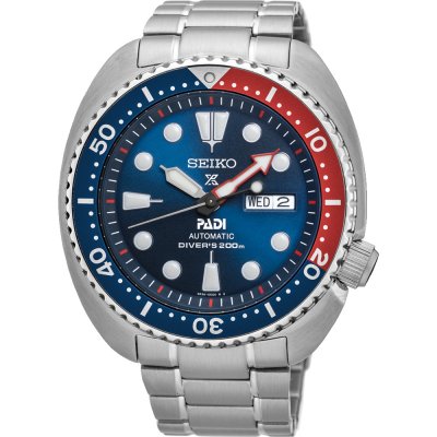 Zilveren duikhorloge met blauwe wijzerplaat, rode en blauwe lunette, en datumaanduiding.