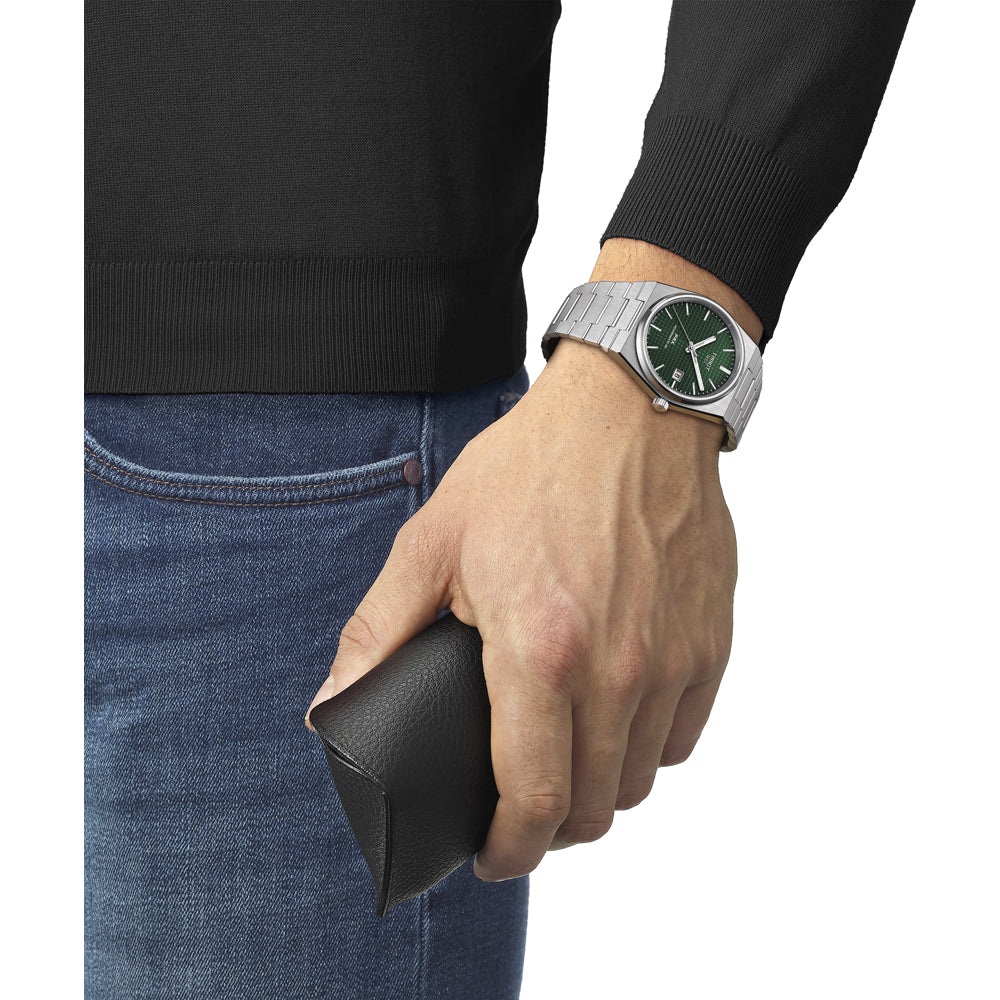 Een persoon draagt een Tissot PRX Powermatic 80 van Tissot met saffierglas en houdt een portemonnee vast.