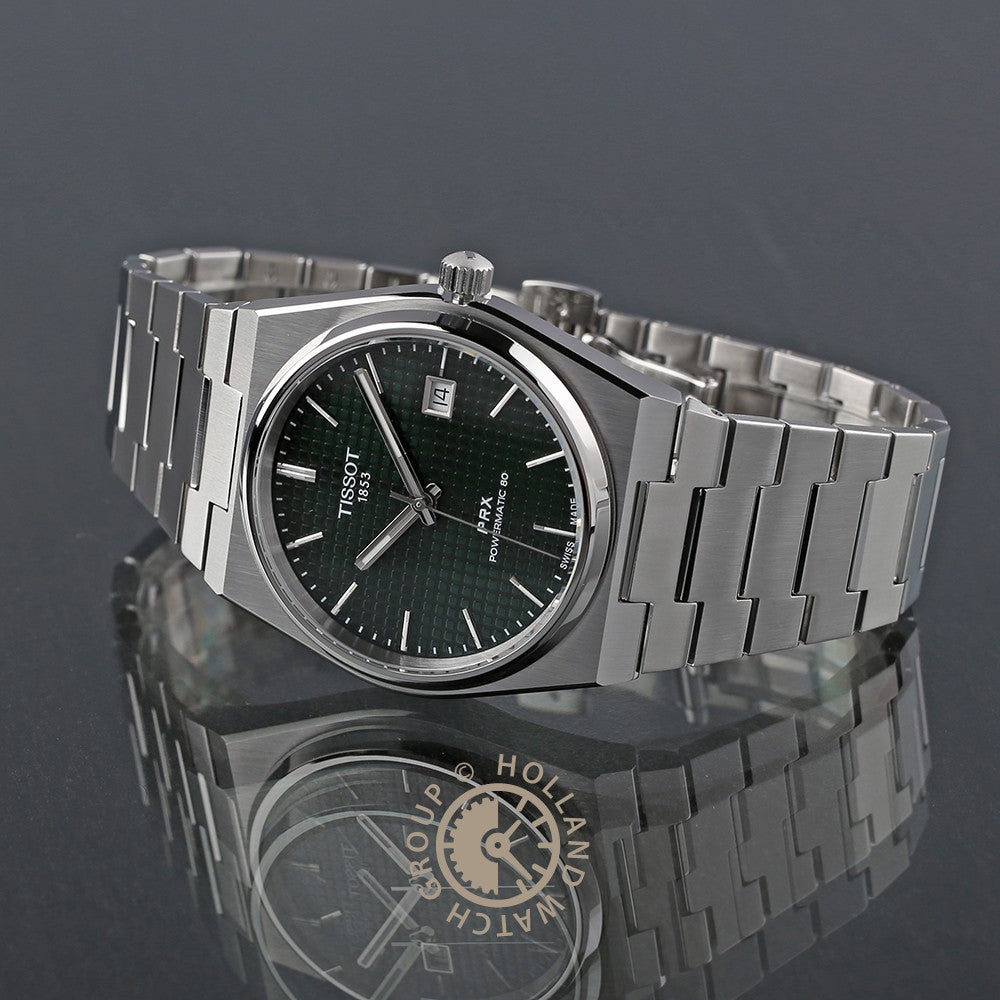 De Tissot PRX Powermatic 80 van Tissot heeft een roestvrijstalen kast, een wijzerplaat met groene structuur, zilverkleurige markeringen, datumweergave, Saffierglas en een Zwitsers automatisch uurwerk. Weergegeven op een reflecterend oppervlak.